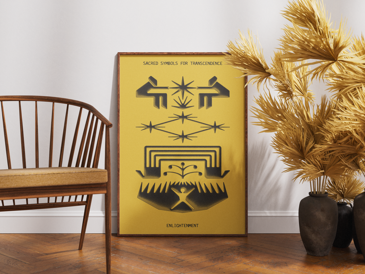A framed art print featuring black sacred geometry and symbolic designs on a mustard yellow background, leaning against a white wall on a wooden floor next to a wooden chair and dried palm branches in dark vases.